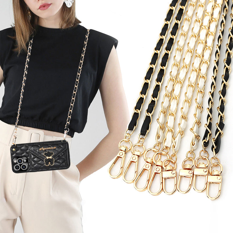 A black leather crossbody purse with a gold chain strap is displayed next to multiple strands of similar chains.