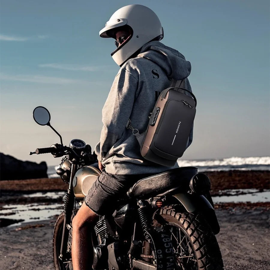 Una persona con casco y sudadera está sentada en una motocicleta con una bolsa cruzada multifuncional.