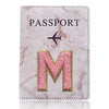 Carátula de pasaporte de mármol rosa y blanco con una M dorada en relieve y un ícono de avión.