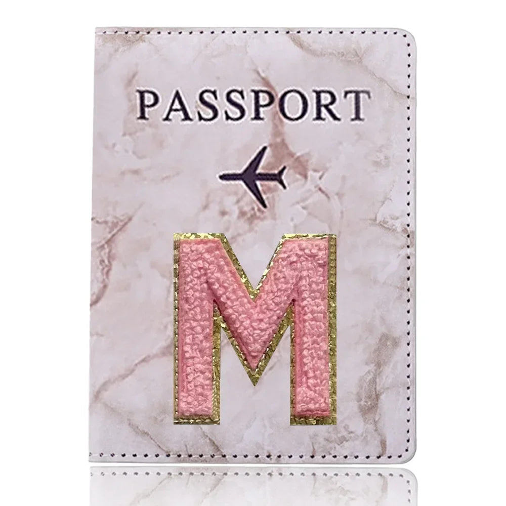 Carátula de pasaporte de mármol rosa y blanco con una M dorada en relieve y un ícono de avión.