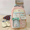 A pink and cream campus backpack with a light blue trim and a green accent, featuring a clear pocket and decorative elements.