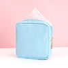 Helle blaue tragbare Tasche zum Aufbewahren von Damenbinden, mit einer gefalteten rosa Taschentuch darin sichtbar.