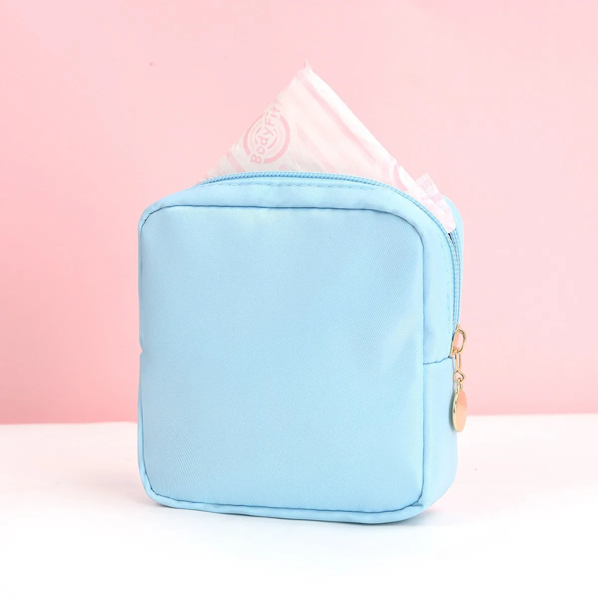 Helle blaue tragbare Tasche zum Aufbewahren von Damenbinden, mit einer gefalteten rosa Taschentuch darin sichtbar.