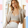 A woman models an ivory fleece crossbody belt bag worn over a sports bra and light-colored athletic wear.