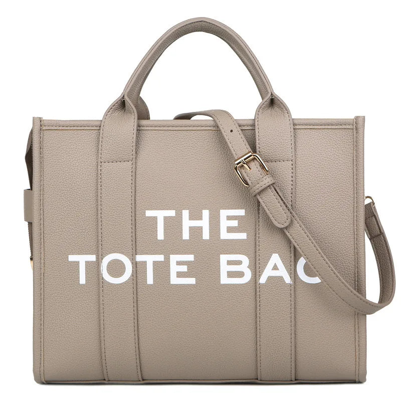 Sac tote en PU beige de luxe designer avec l'inscription THE TOTE BAG sur le devant.
