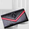 Black alligator pattern leather clutch bag with red trim shown diagonally.