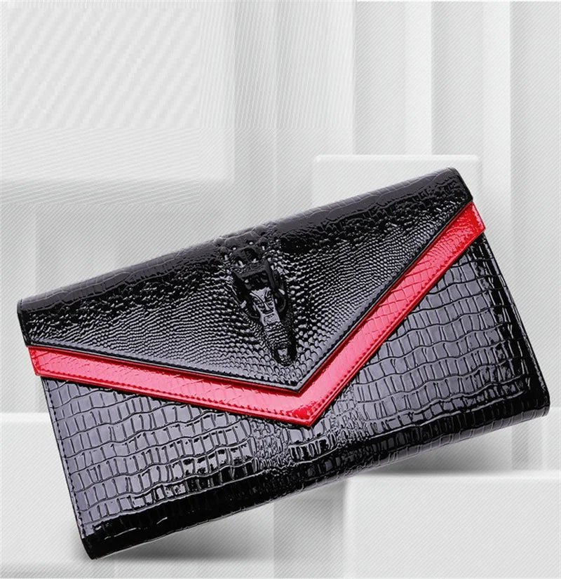 Black alligator pattern leather clutch bag with red trim shown diagonally.