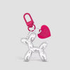 A silver balloon dog keychain charm with a pink heart and a pink loop.
