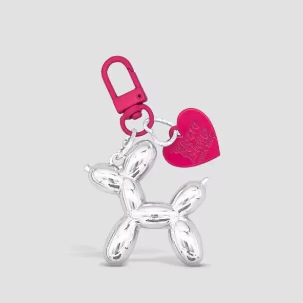 A silver balloon dog keychain charm with a pink heart and a pink loop.