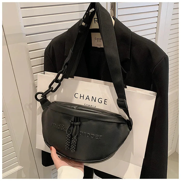 Black PU leather crossbody saddle bag with a chain strap displayed on a white box.