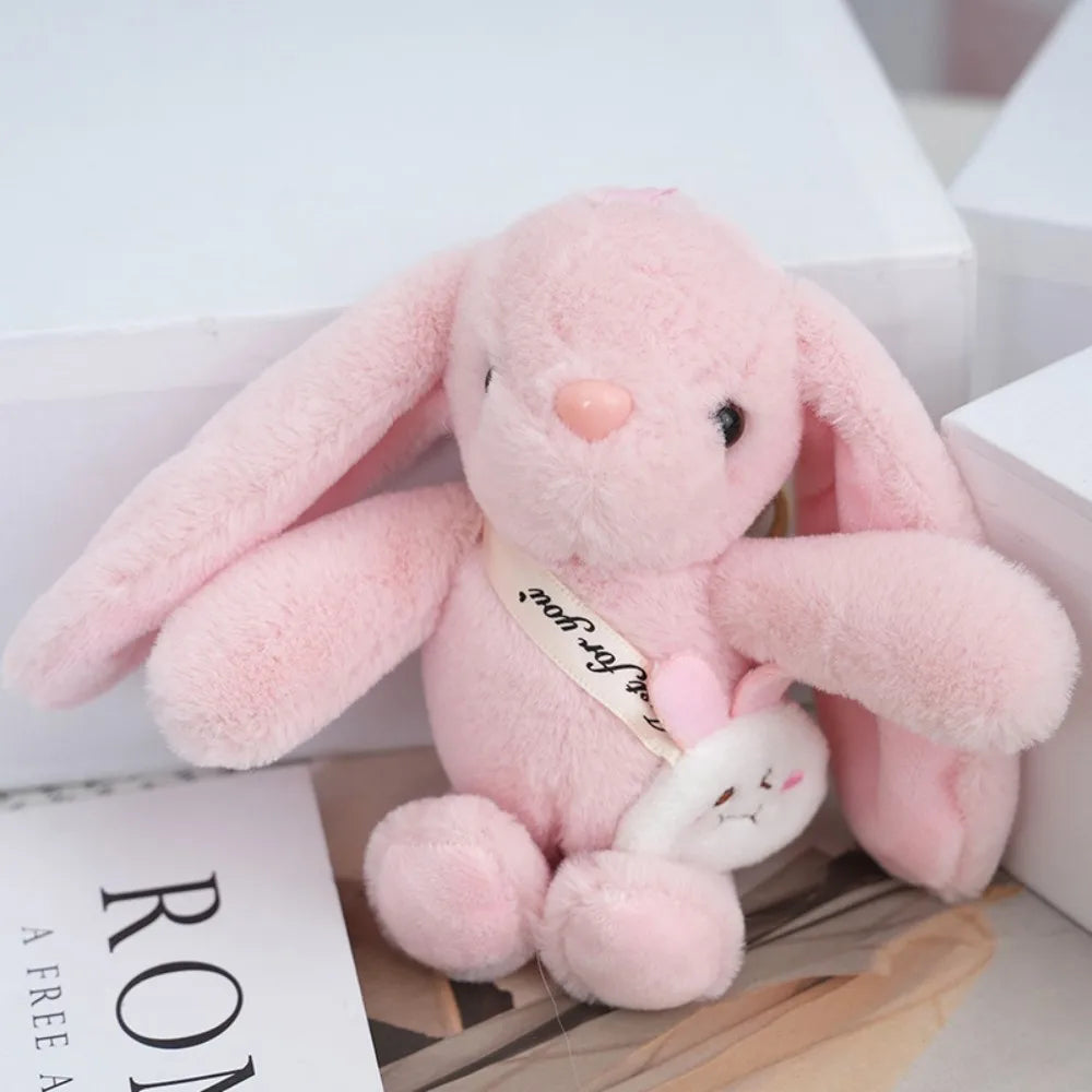 A pink plush rabbit toy with long ears sitting inside a white box.