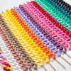A vibrant rainbow of matte acrylic choker necklaces arranged in a diagonal line.
