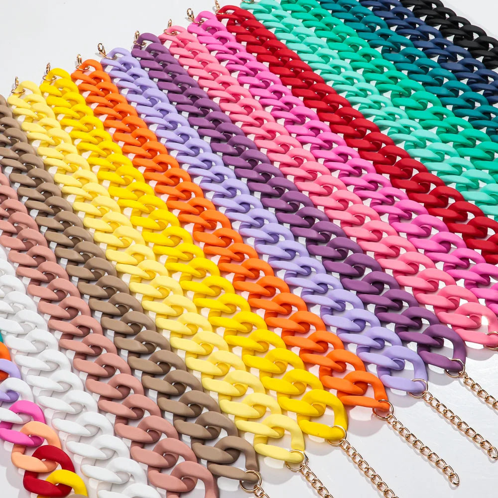A vibrant rainbow of matte acrylic choker necklaces arranged in a diagonal line.