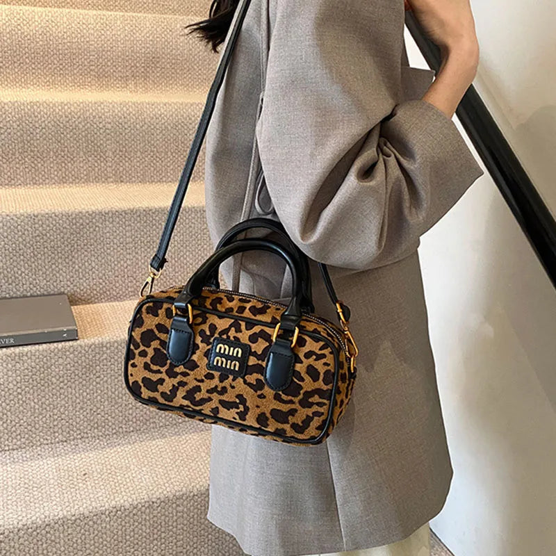 Eine Frau hält eine braune Leopardenmuster-Designer-Hobo-Tasche auf einer Treppe.