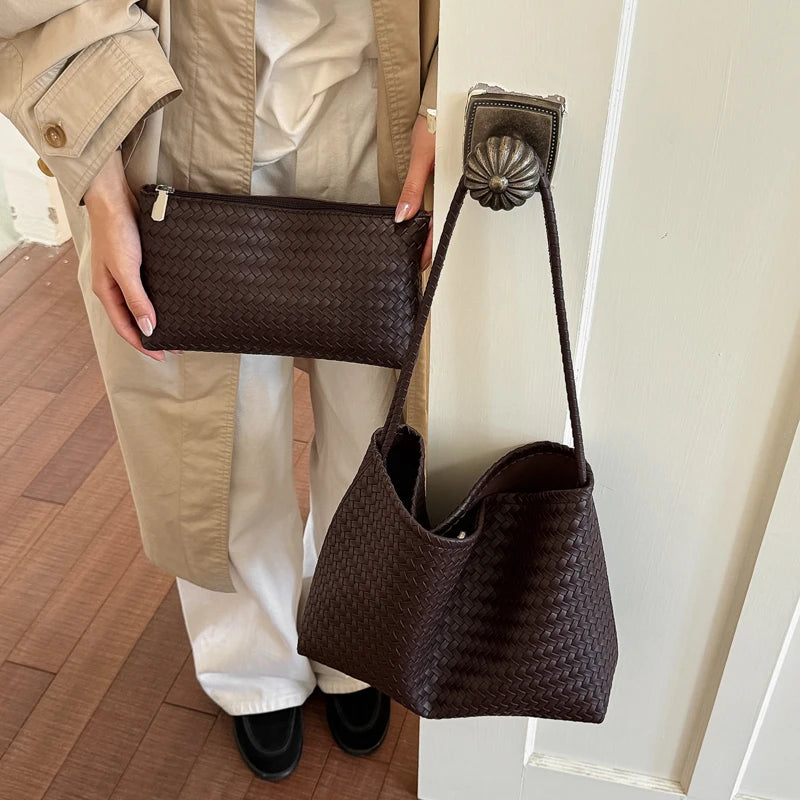 A brown quilted leather bucket shoulder bag is displayed hanging on a white door with a beige trench coat visible.