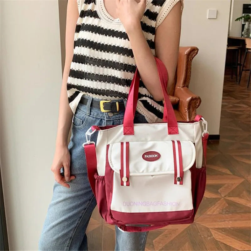 Eine Frau hält eine weiße und rosa Nylon-Tasche mit roten Riemen vor einem hellen Hintergrund.