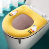 A yellow plush waterproof toilet seat cover with embroidered faces of a bird and a fish.
