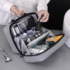 A hand is opening a gray portable waterproof travel toiletry bag filled with various grooming products.