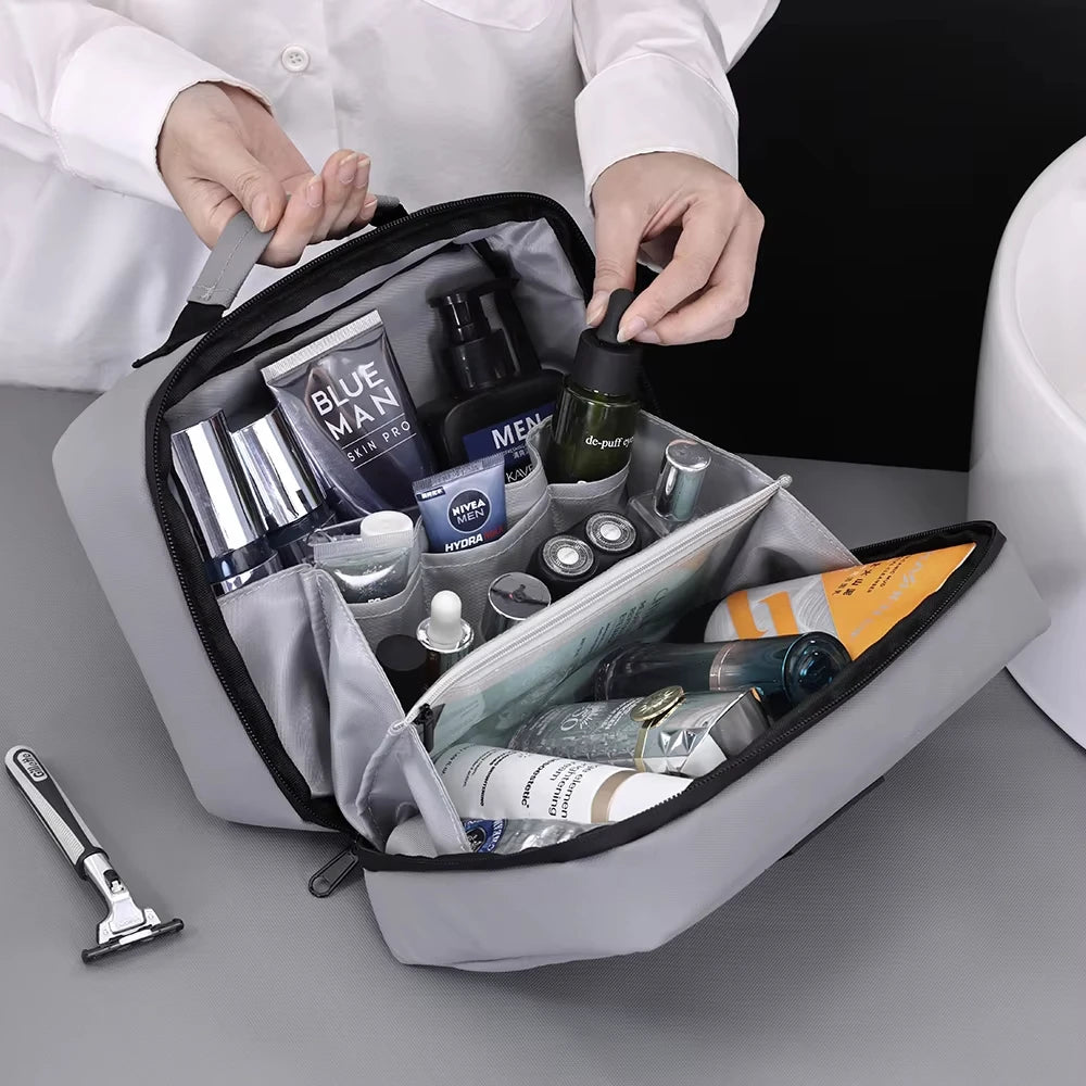A hand is opening a gray portable waterproof travel toiletry bag filled with various grooming products.