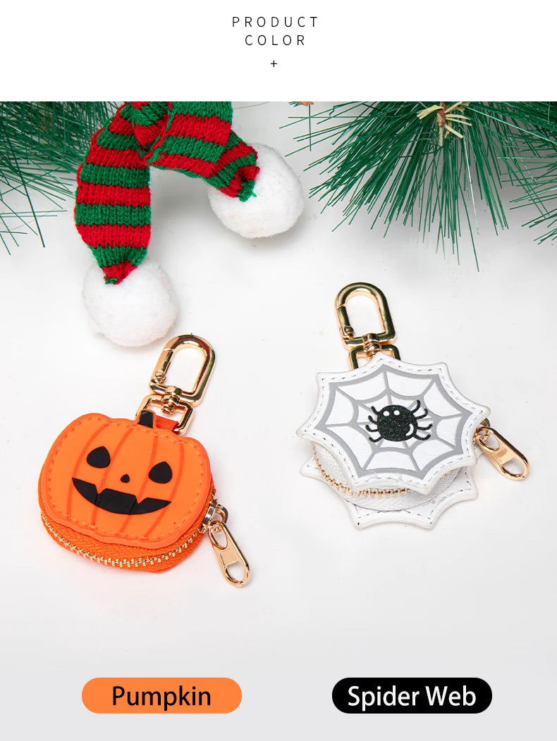 Cartera de monedas en forma de calabaza junto a un dije de telaraña y follaje navideño.