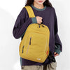 A woman wearing a purple long-sleeved shirt carries a yellow fashion commuter daypack on her shoulder.