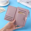 A hand holds a pink leather wallet with card holder and coin pocket on a light blue surface.