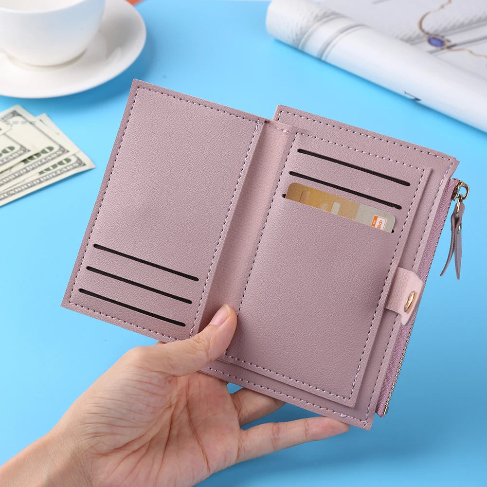 A hand holds a pink leather wallet with card holder and coin pocket on a light blue surface.