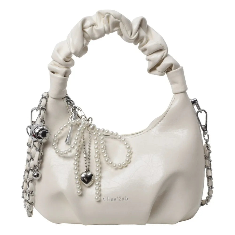 Clutch de cuero color crema con detalle de lazo y adornos de perlas.
