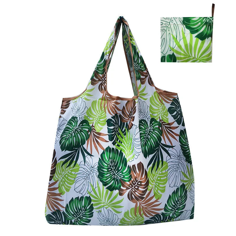 A reusable tote bag featuring a vibrant tropical leaf pattern in shades of green and brown on a white background.
