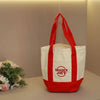 A white canvas bag with red handles and trim is displayed on a light surface.