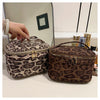 A brown faux suede cosmetic bag with a leopard print pattern is shown next to a mirror.