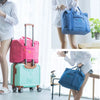 A woman is shown with a pink foldable travel duffel bag and a light green rolling suitcase.