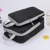 A stack of black and gray vertical travel organizer bags is shown on a white surface.