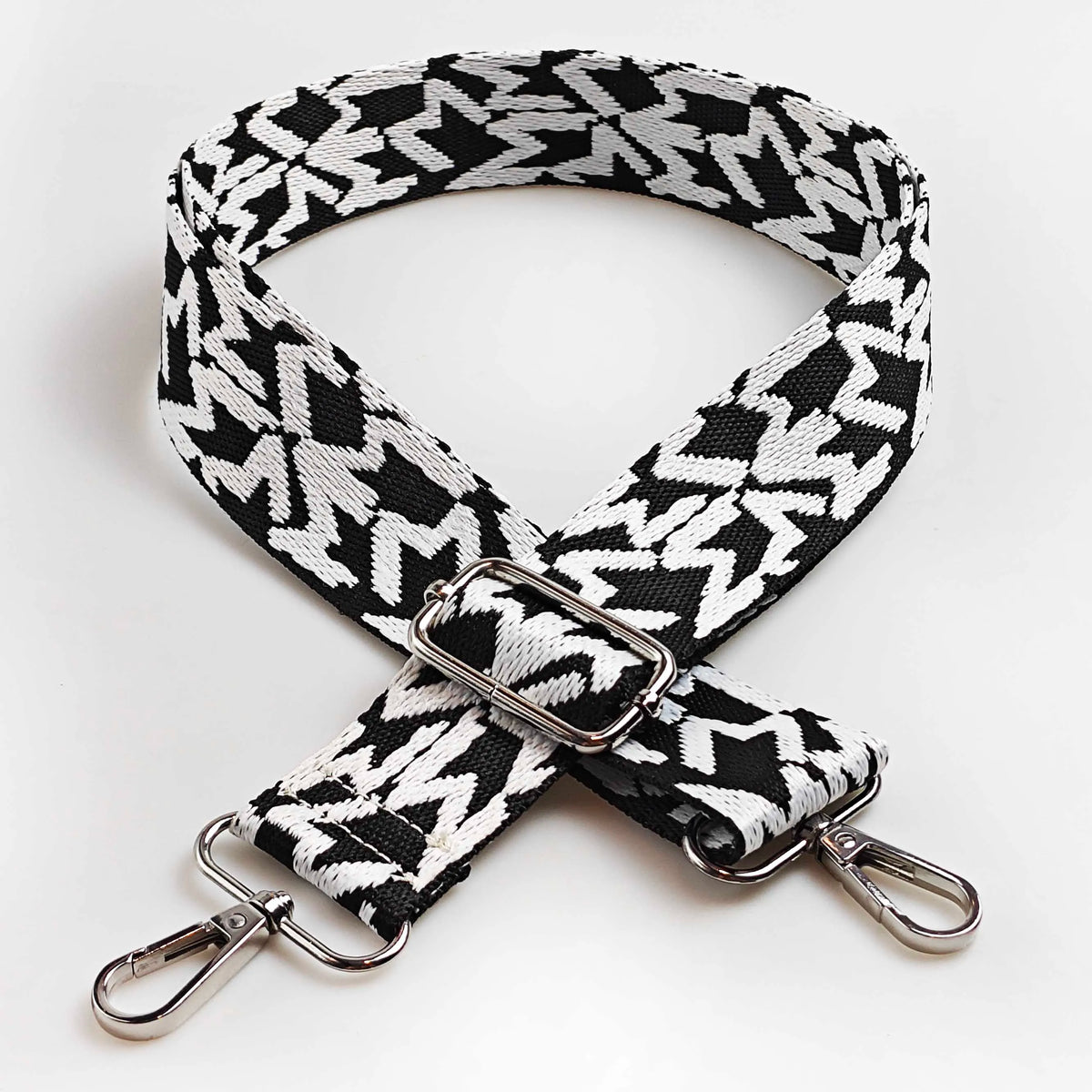 A black and white jacquard patterned strap for an adjustable wide crossbody bag.