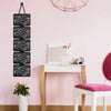 A wall-mounted organizer displaying various necklaces and earrings in a multi-tiered display against a pink wall.