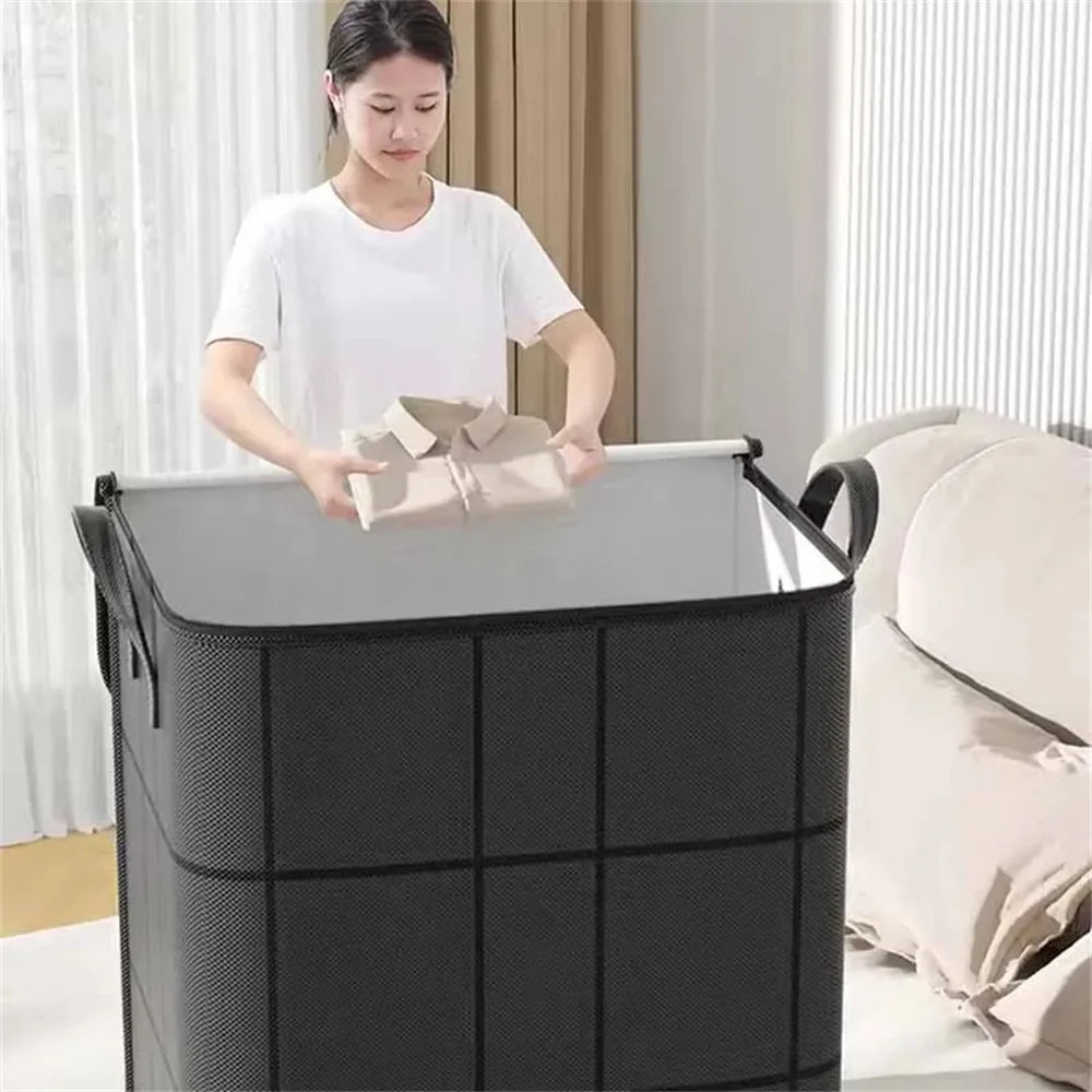 A woman is placing a folded item into a large black foldable non-woven storage bag.