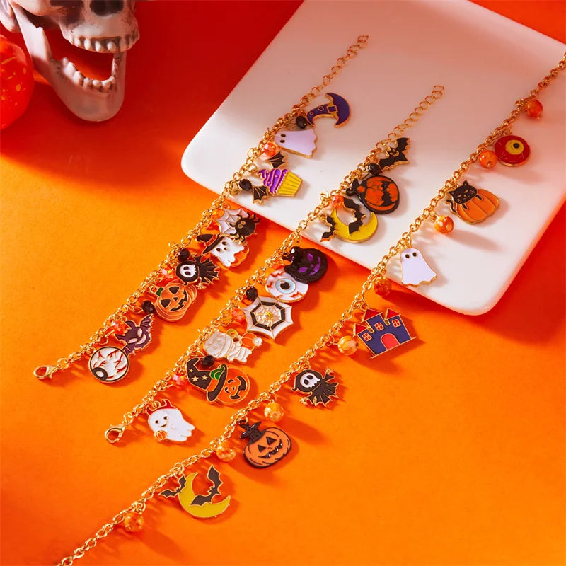Gold charm bracelets featuring Halloween themed charms like pumpkins and ghosts displayed on a white surface.