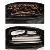 A dark leather crossbody bag is shown open, revealing a patterned lining and a white electronic device.