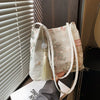 Bolso de hombro de seda jacquard retro color crema con tiras blancas, junto a una persiana.
