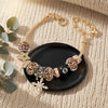 A gold-toned leopard print bracelet featuring black and gold beads and a charm on a dark surface.