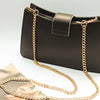 A black leather handbag with a gold metal chain strap is shown against a white background.