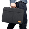 Une housse de protection laptop mince gris foncé tenue par une personne portant un jean foncé.