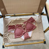 A red plaid bikini set with a halter top and low-rise waist is displayed on a wooden rack.