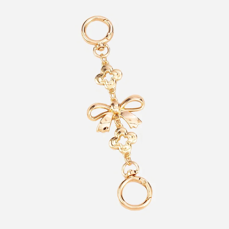 Gold metal purse chain strap with a decorative bow charm and a loop end