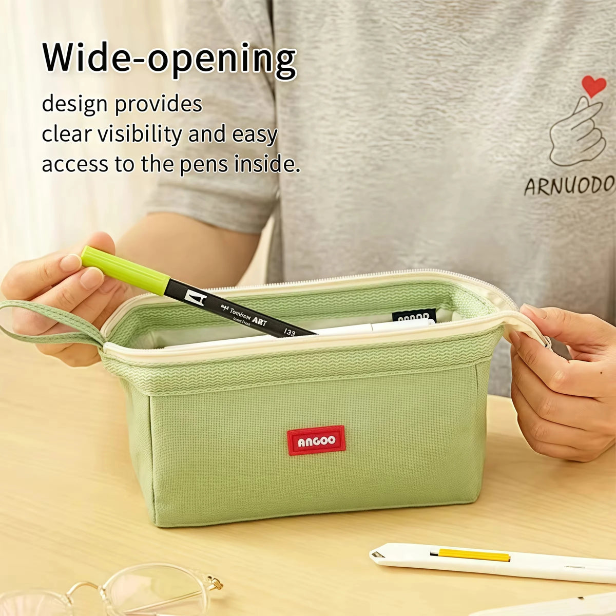 A light green pencil case is shown open, demonstrating wide-opening design for easy access to pens and pencils.