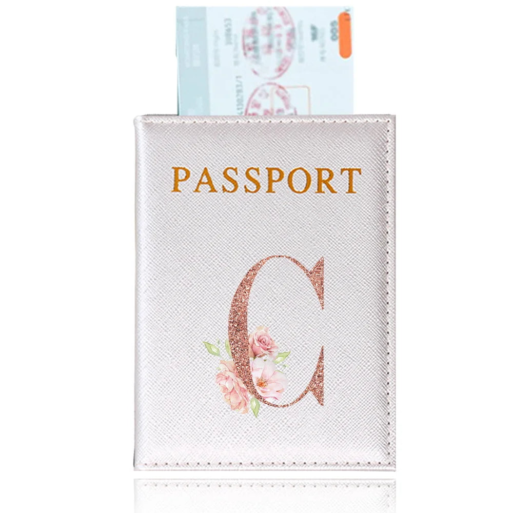 A pink leather passport holder featuring a gold initial C and floral embroidery.