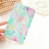 A hand holds a pink and green floral patterned card holder keychain against a white background.