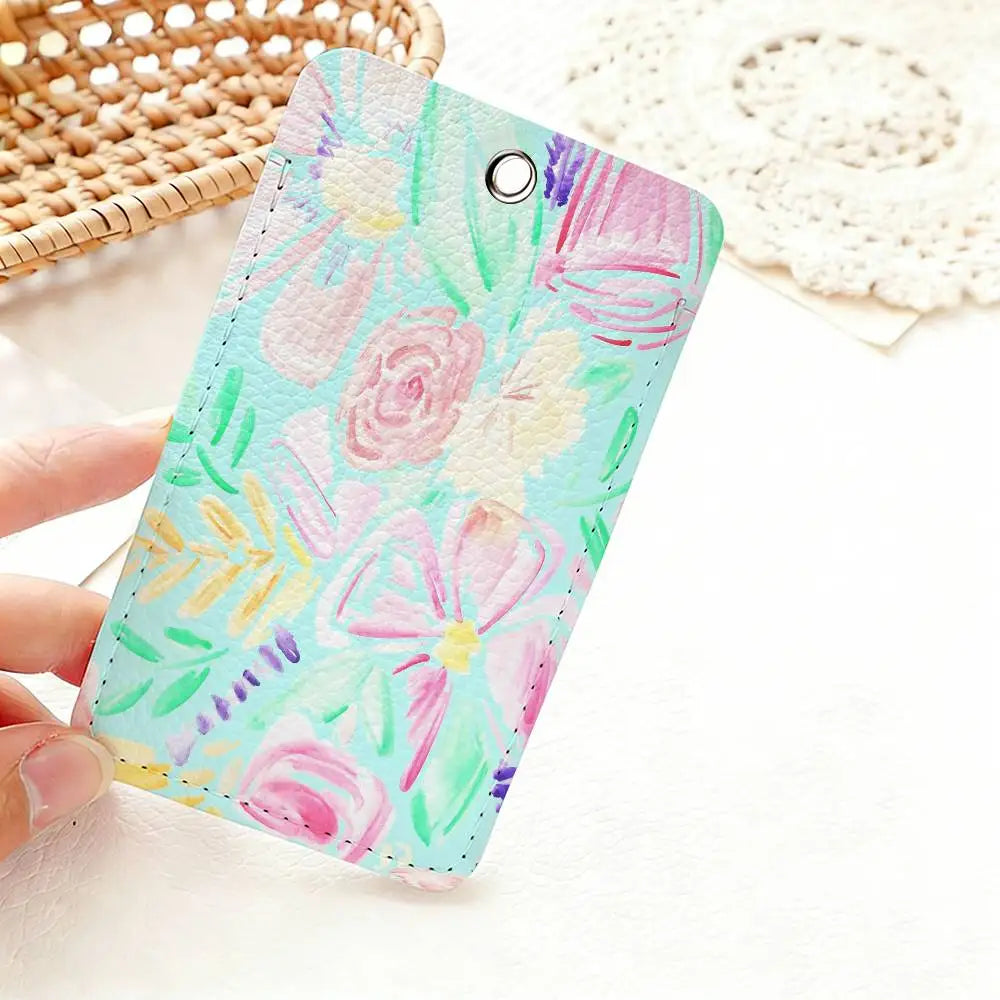 A hand holds a pink and green floral patterned card holder keychain against a white background.