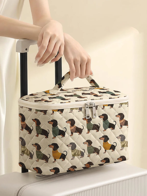 A quilted cosmetic travel bag featuring a dachshund print is being held by a person's hand.