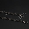 A close-up of a black metal chain strap with adjustable links and a clasp, shown against a dark background.